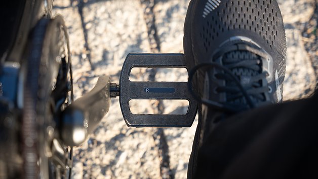 Ein Fuß auf einem Fahrradpedal mit der Bezeichnung 'R' auf einem felsigen Untergrund.