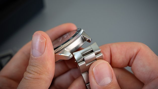 Eine Person hält eine Withings ScanWatch Nova und passt das Metallarmband an.