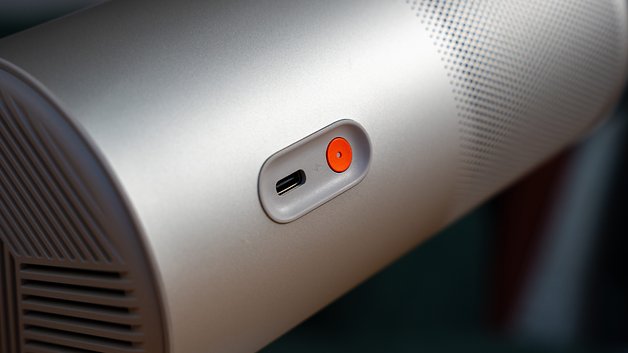 Nahaufnahme eines silbernen Geräts mit einem USB-C-Anschluss und einem roten Knopf.