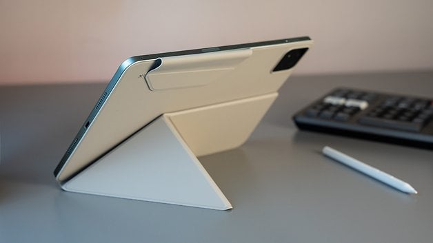 A Xiaomi Pad 7 on a stand, with a stylus nearby and a calculator in the background.