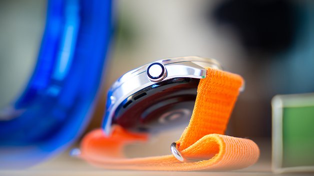 Nahaufnahme einer Xiaomi S4-Uhr mit einem orangefarbenen Armband und einem silbernen Gehäuse.
