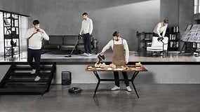 Un homme utilisant un aspirateur pendant que d'autres travaillent dans la maison.