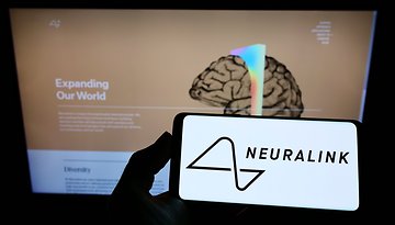 Smartphone mit Neuralink-Logo vor Monitor mit Neuralink-Website