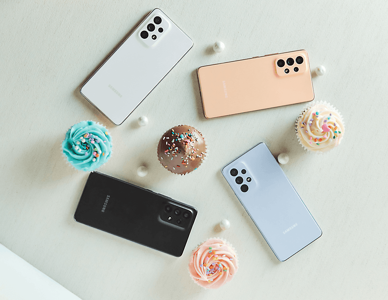 Das Galaxy A53 in allen vier Farben, dazwischen liegen Süßigkeiten.