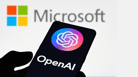 Handy mit OpenAI-Logo vor großem Microsoft-Logo