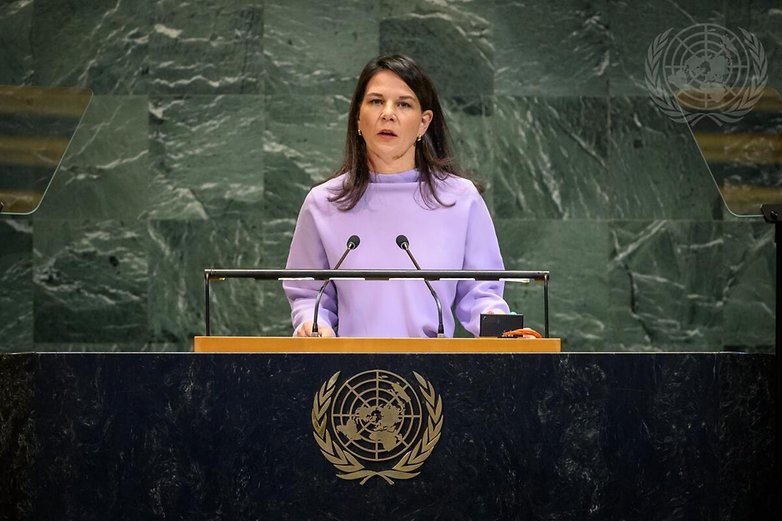 Annalena Baerbock im lila Oberteil spricht an einem Podium mit dem UN-Emblem im Hintergrund.