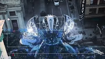 Eine große Robotergestalt ragt über eine Stadtstraße, mit einer digitalen Überlagerung, die eine Überwachungsperspektive anzeigt.