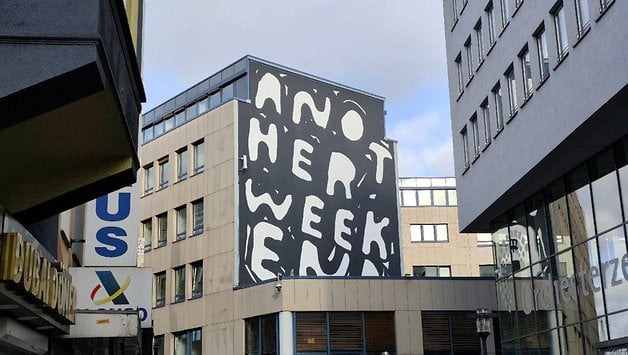 Un bâtiment avec une fresque affichant le texte 'Another Weekend'.