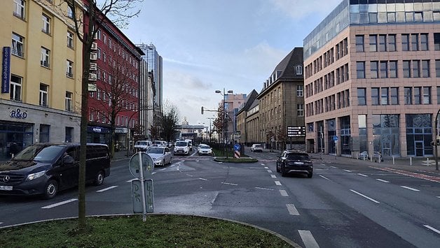 Une rue urbaine animée avec des bâtiments de chaque côté et des véhicules sur la route.