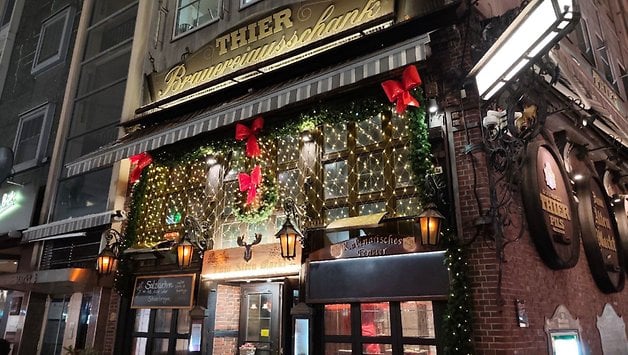 Eine wunderschön dekorierte Restaurantfassade mit festlichen Lichtern und Schleifen, mit dem Namen 'THIER' auf dem Schild.