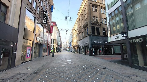 Une vue tranquille de la rue avec des magasins tels que Only, Jack & Jones et Zara sous un ciel dégagé.