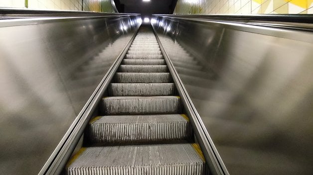 Rolltreppe, die in einem gut beleuchteten Raum nach oben führt.