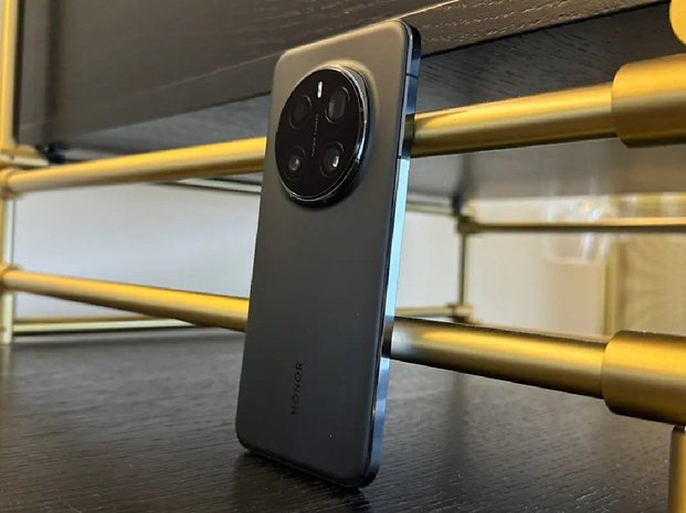 Ein schwarzes Honor Magic 7 Pro-Smartphone lehnt an einem goldenen Regal.