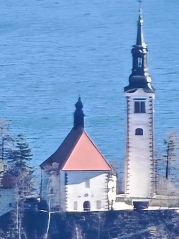 Eine Ansicht einer Kirche mit hohem Turm neben einem Gewässer.