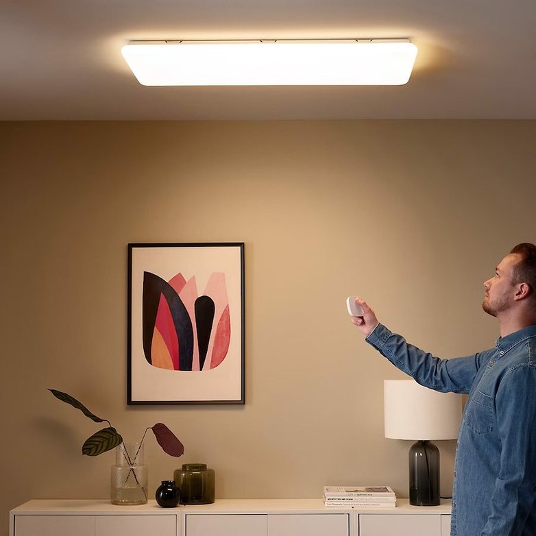 Die smarte Leuchte hängt in einem Wohnzimmer an der Decke und wird per Fernbedienung kontrolliert
