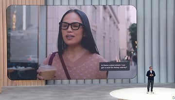 Eine Frau mit Brille fragt nach einem Geschäft in der Nähe, während sie ein Getränk hält. Text: Gibt es ein Geschäft, wo ich eine Karte für Kelsey in der Nähe bekommen kann?