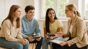 Eine Gruppe von vier Jugendlichen sitzt zusammen und diskutiert mit einer Frau in einem professionellen Umfeld.