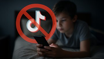 Ein Junge verwendet ein Smartphone im Bett mit einem überlagerten 'kein TikTok'-Symbol.