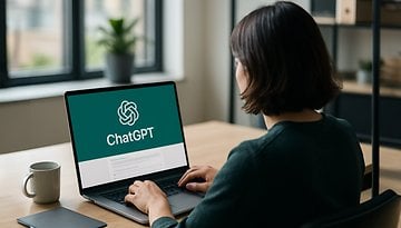 Eine Person arbeitet an einem Laptop mit dem ChatGPT-Logo, daneben eine Kaffeetasse.