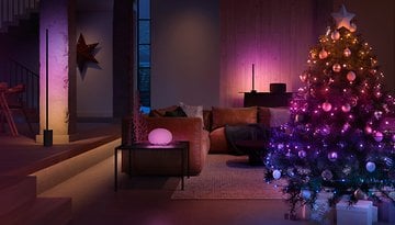 A cozy living room decorated with a colorful Christmas tree and ambient lighting.