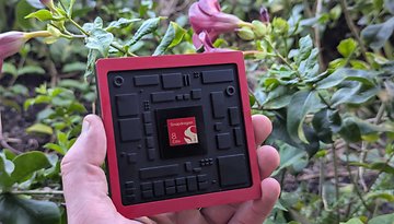 A person holding a Qualcomm Snapdragon 8 Elite Gen 5 chip surrounded by greenery.