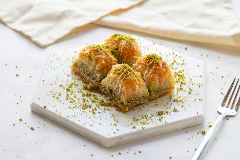 Une assiette de baklava surmontée de pistaches concassées.