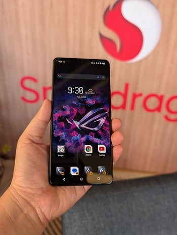 A person holding an Asus ROG Phone 9 displaying a colorful screen with app icons.