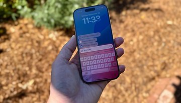 An outdoor photo of an iPhone 16 Pro being held in a hand. On the phone you can see the new Siri interface that's coming with iOS 18.1.