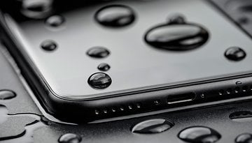 A smartphone with water droplets on its surface, showcasing water resistance.