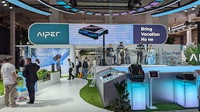 AIPER-Messe-Stand mit dem Slogan 'Bring Vacation Home' und einer Band, die auftritt.
