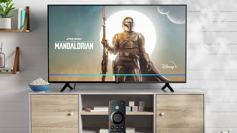 Der Amazon Fire TV-4 zeigt 'Star Wars: The Mandalorian' mit einer Fernbedienung darunter. Popcorn in einer Schüssel daneben.