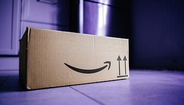 Ein Pappkarton mit dem Amazon-Logo auf einem lila Boden.