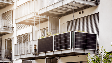 Ein Balkon mit Solarpanels an einem modernen Wohngebäude.