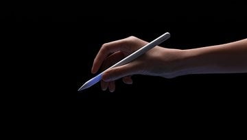 Eine Hand hält einen Baseus-Stylus mit leuchtender Spitze vor schwarzem Hintergrund.
