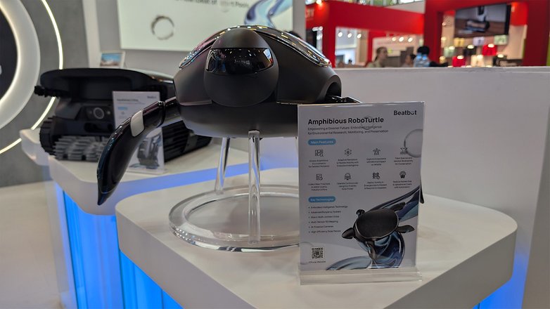 Eine schwarze amphibische Roboterschildkröte, die mit einem Schild, das ihre Funktionen beschreibt, auf einer Technologiemesse ausgestellt ist. Eine schwarze amphibische Roboterschildkröte, die mit einem Schild, das ihre Funktionen beschreibt, auf einer Technologiemesse ausgestellt ist.