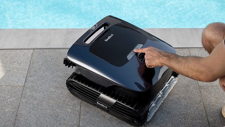 Eine Person stellt den Beatbot Aquasense 2 Pro Roboter-Poolreiniger neben einem Schwimmbecken ein.