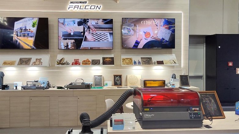 Creality Falcon2 Pro Laserschneider auf der IFA 2024, mit Bildschirmen, die Projekte und Muster zeigen.