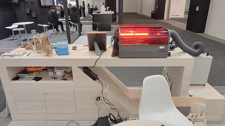 Ein Creality Falcon 2 Pro Laser Cutter auf einem Ausstellungstisch mit verschiedenen Materialien darum herum.