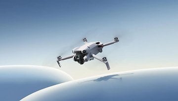 Eine DJI Mini 4 Pro-Drohne fliegt vor einem klaren blauen Himmel.