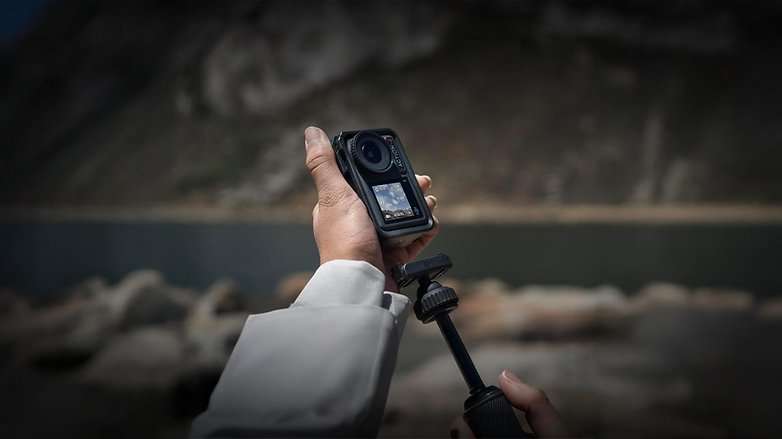 Eine Person hält eine DJI Osmo Action 4 Kamera auf einem Stativ in der Nähe eines Gewässers. Eine Person hält eine DJI Osmo Action 4 Kamera auf einem Stativ in der Nähe eines Gewässers.