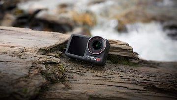 DJI Osmo Action 5 Kamera auf einer Holzoberfläche neben Wasser.
