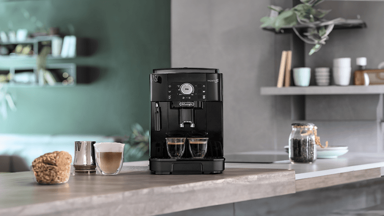 Eine De'Longhi Magnifica S ECAM 11.112.B Kaffeemaschine auf einer Küchenzeile mit zwei Tassen Kaffee. Eine De'Longhi Magnifica S ECAM 11.112.B Kaffeemaschine auf einer Küchenzeile mit zwei Tassen Kaffee.