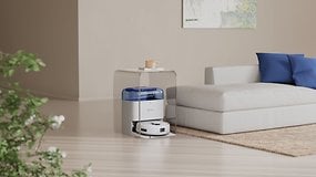 Ein weißer Ecovacs Deebot Mini Saugroboter neben einem Sofa und einer Pflanze in einem modernen Wohnzimmer.