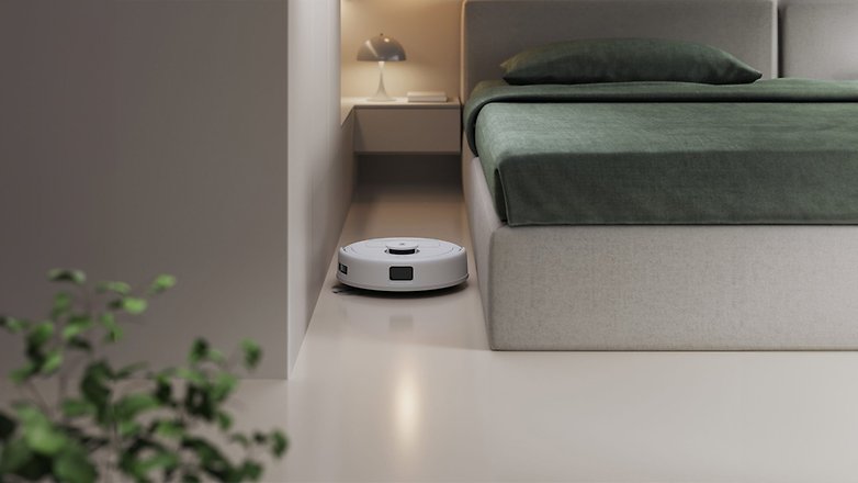 Ein weißer ECOVACS DEEBOT Mini Saugroboter in der Nähe eines Bettes in einem modernen Schlafzimmer. Ein weißer ECOVACS DEEBOT Mini Saugroboter in der Nähe eines Bettes in einem modernen Schlafzimmer.