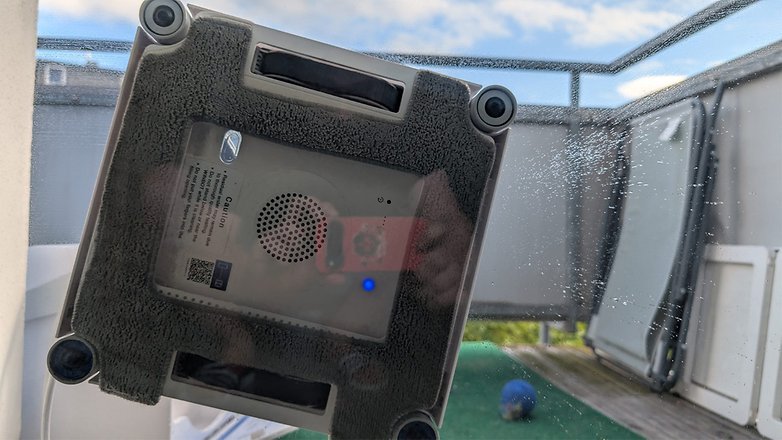 Ein Fensterputzroboter, der an einer Glasoberfläche haftet, mit sichtbarem blauen Anzeigeleuchten. Ein Fensterputzroboter, der an einer Glasoberfläche haftet, mit sichtbarem blauen Anzeigeleuchten.