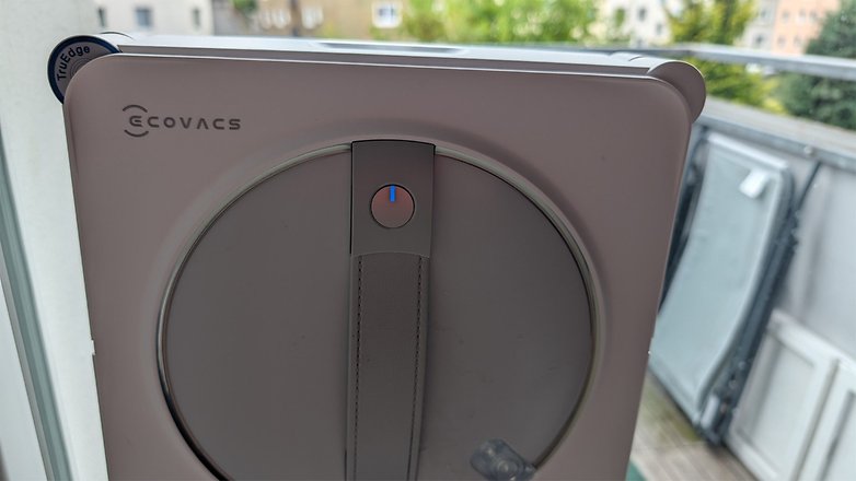 Nahaufnahme des Ecovacs Winbot W2S Omni Fensterputzroboters mit einem blauen Knopf. Nahaufnahme des Ecovacs Winbot W2S Omni Fensterputzroboters mit einem blauen Knopf.