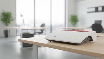 Fritz!Box 7590 AX WLAN-Router auf einem Holztisch in einer modernen Büroumgebung.