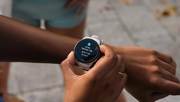 Eine Person überprüft eine Garmin Forerunner 165 Music Smartwatch, die Trainingsdetails anzeigt.