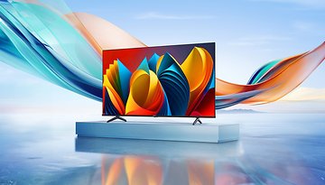 Ein Hisense E7NQ-Fernseher zeigt lebendige abstrakte Farben auf einem eleganten Stand am Wasser.