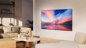 Ein modernes Wohnzimmer mit einem LG OLED77B4 Fernseher, der einen bunten Sonnenuntergang über Wasser zeigt.